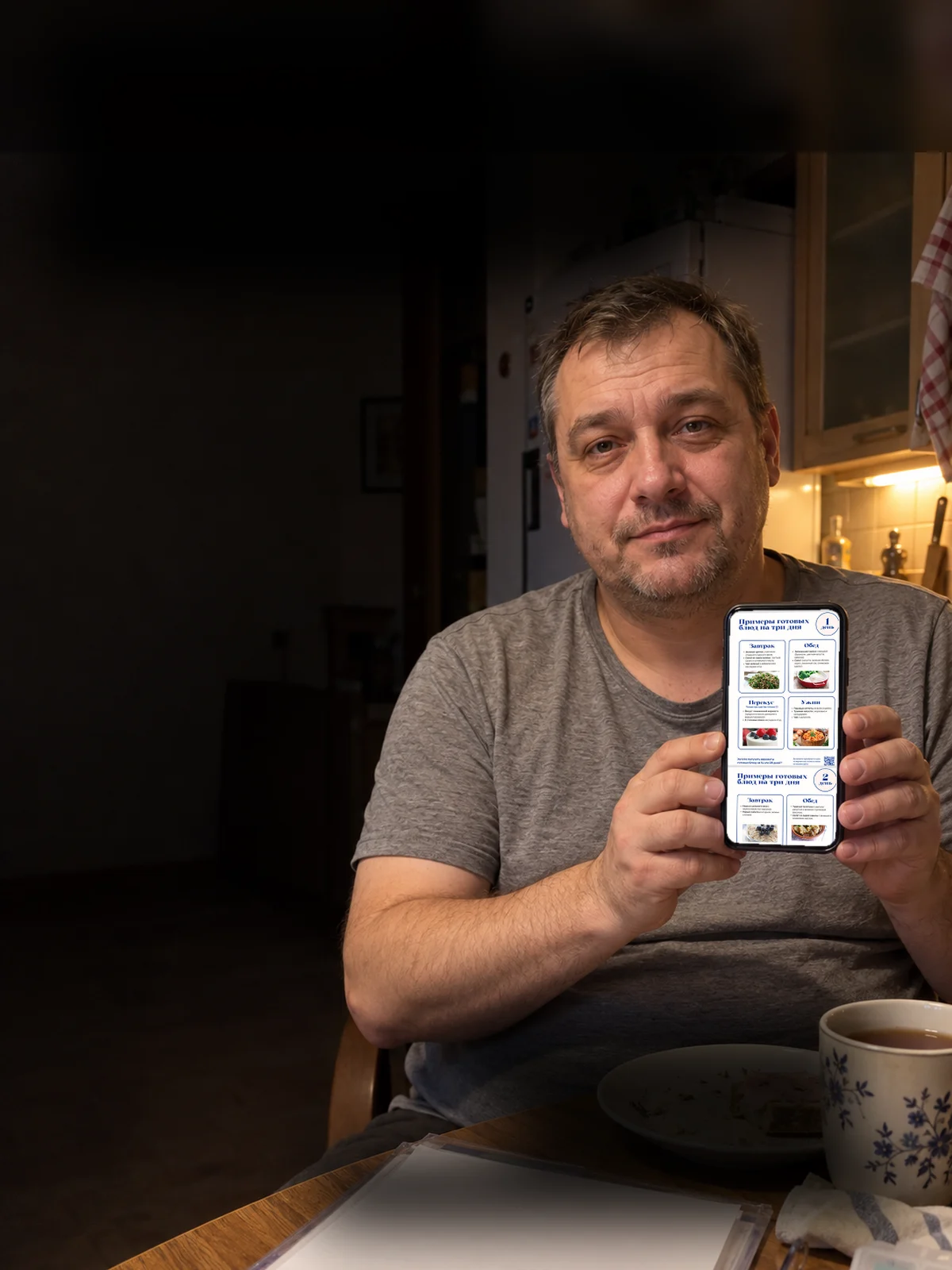 Мужчина на кухне показывает телефон: на экране меню на три дня из плана «Жировой гепатоз»
